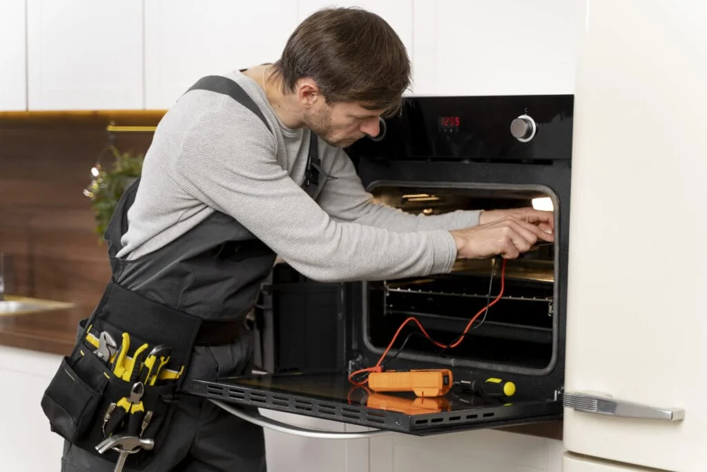A man performing appliance repair in an oven.
