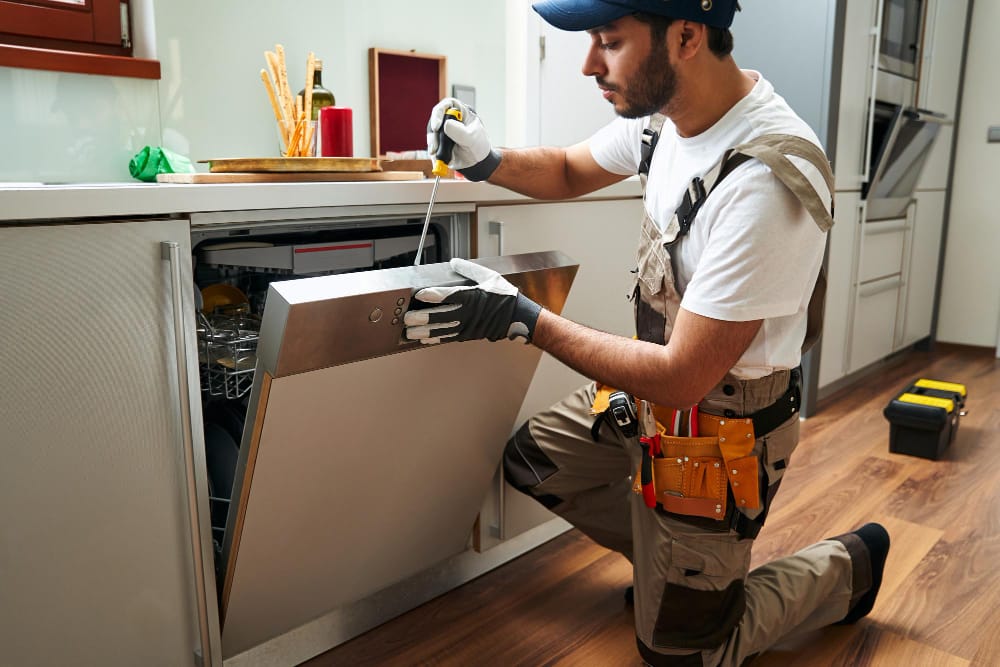 Appliance repair technician fixing broken refrigerator in Malden Massachusetts home