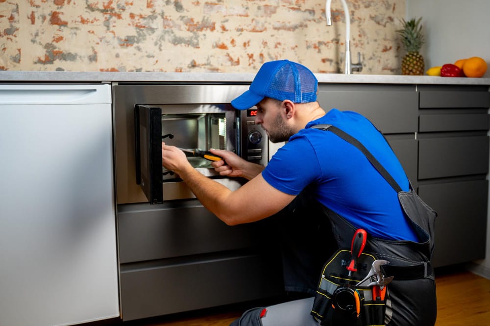 Professional appliance technician repairing oven in Malden MA home kitchen