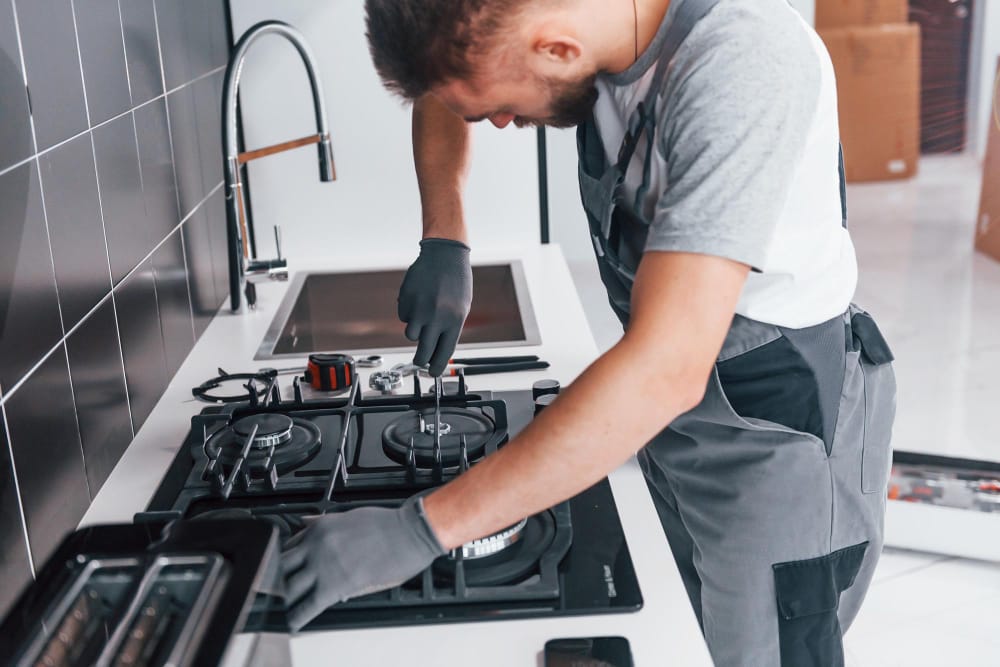 Professional technician repairing stove burner and control panel in Malden kitchen